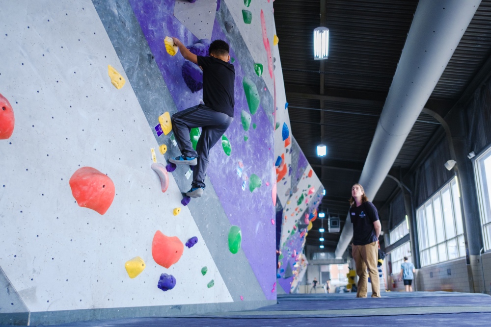 A Pittsburgh Public School student scales a wall at ASCEND Climbing Gym on Pittsburgh's South Side. This class is part of the district's COVID Compensatory Services program, designed to help students with disabilities make up for the supports they lost access to during the pandemic. (WESA)