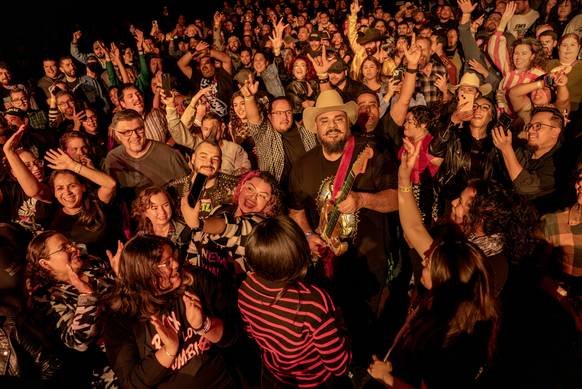 Pedro Zapata, known as Pedro Pistolas, a guitar player and vocalist for Spaghetti Cumbia, plays his guitar while surrounded by a crowd at a show at the El Rey Theatre in Los Angeles on Dec. 29, 2024.