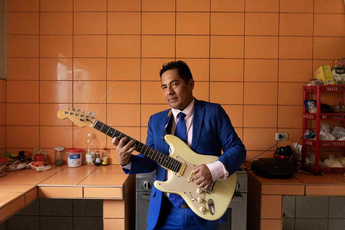 Berardo Hernández Jr., known as Manzanita Jr., holds his guitar in his kitchen in Lima, Peru, on Nov. 2, 2024. Hernández's father, Manzanita, is known for having a part in creating chicha's sound.
