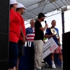 Joey Chestnut (right) holds a gold belt after winning the Fort Bliss hot dog contest, as the Impossible Foods CEO holds a giant check onstage.
