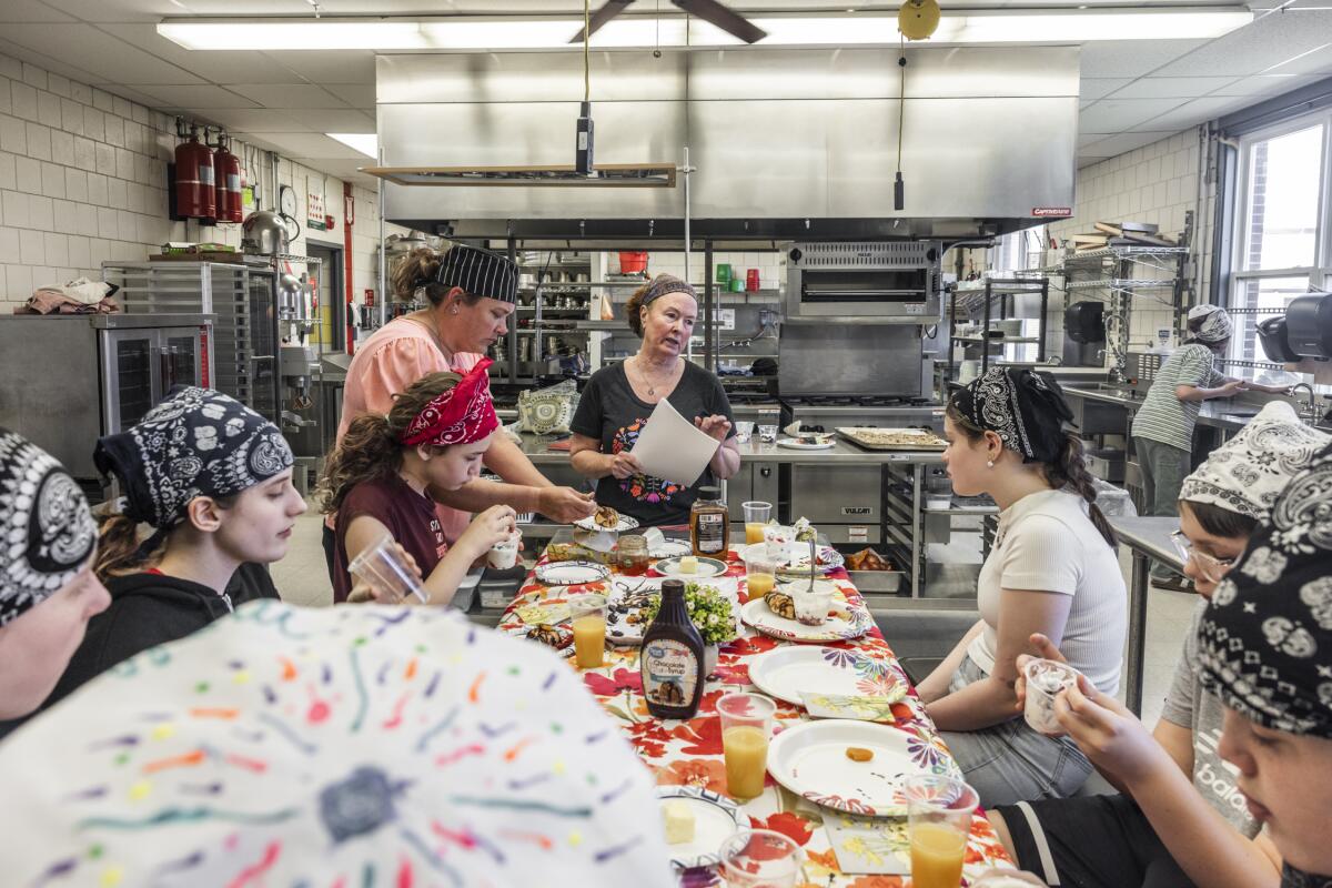 Retired chef and cooking instructor Brenda Madden gathers students around a table to enjoy their creations from the afternoon's lesson on French cuisine.