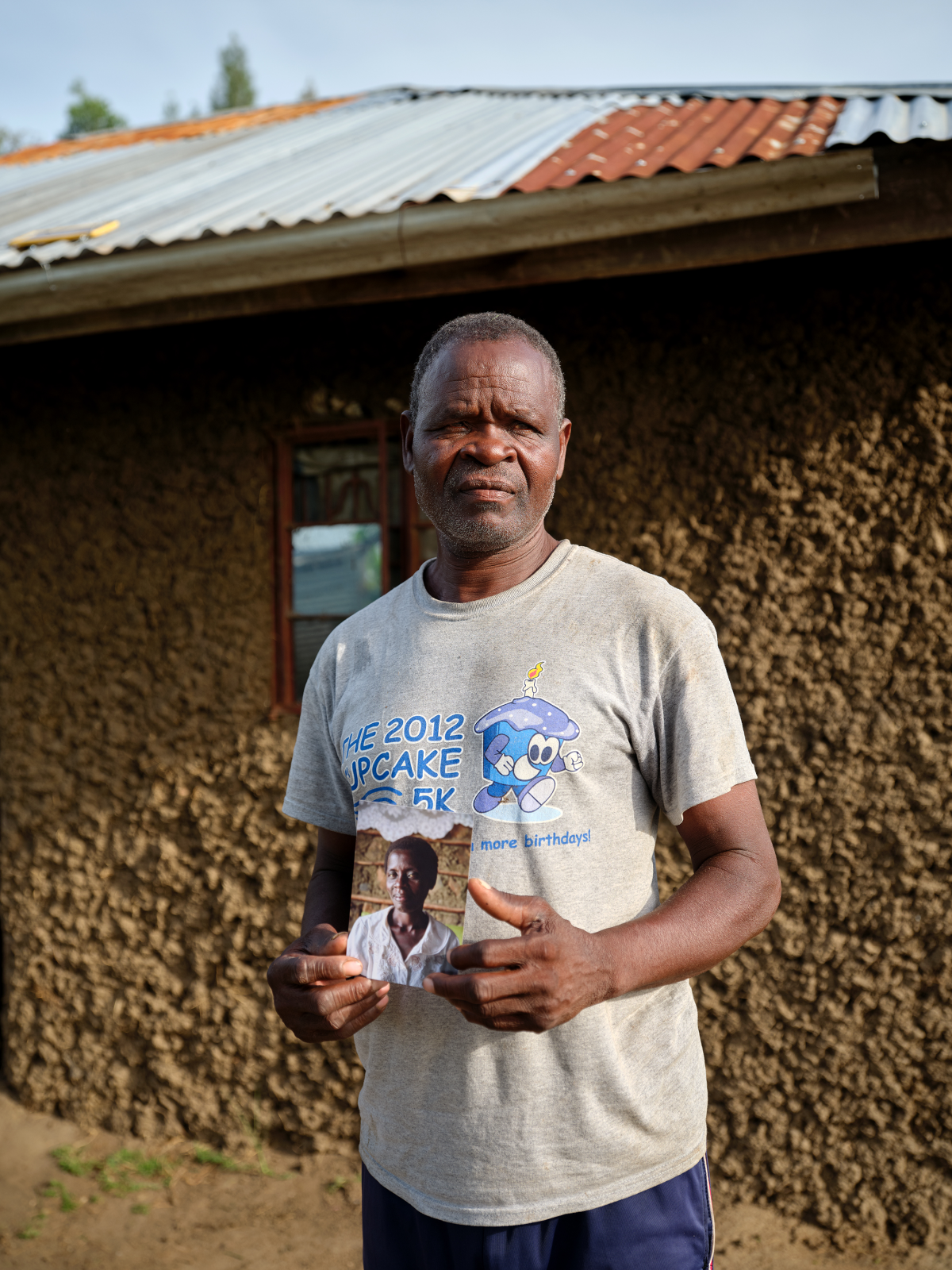 Jack Len'go holds a photo of his wife, Rose Atieno Abongo, who was a member of the No Sex for Fish group. The photo was taken in 2019, when an NPR team first reported on this story. Rose died in October 2024 of complications from HIV/AIDS. Len'go says she'd stopped taking her preventive drugs because she was not getting proper nutrition and the pills were making her sick. Rose is buried next to their home.