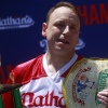 Joey Chestnut holds a trophy and mustard belt after winning the 2022 Nathan's Famous hot dog-eating contest.