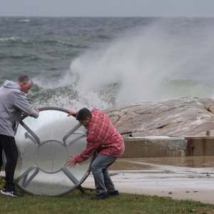 John Garrisi, left, and Gaige Graf move an outdoor table away from the shorefront during the early stages of a nor'easter storm on Friday.