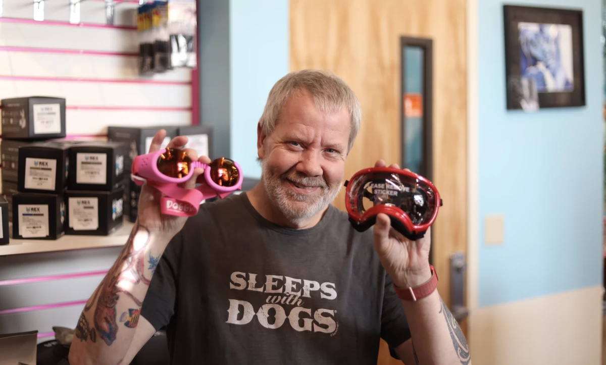 Mark Robokoff, the owner of AK Bark in Anchorage, shows the two models of eye protection available at his pet store.