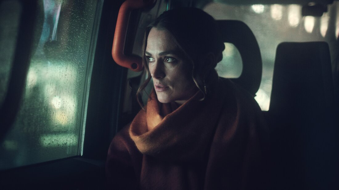 In a still image from Black Doves, Keira Knightley stares out of the window of a car on a rainy day. On the new Netflix series, Knightley plays the wife of a politician and a mom to cute kids. She's also an undercover spy, secretly feeding a covert intelligence agency information about her husband's job.