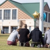Apalachee High School shooting suspect is charged with 4 counts of murder : NPR 5 Students kneel in front of a makeshift memorial in front of Apalachee High School on in Winder, Ga., on Thursday, one day after two students and two teachers were shot and killed at the school.