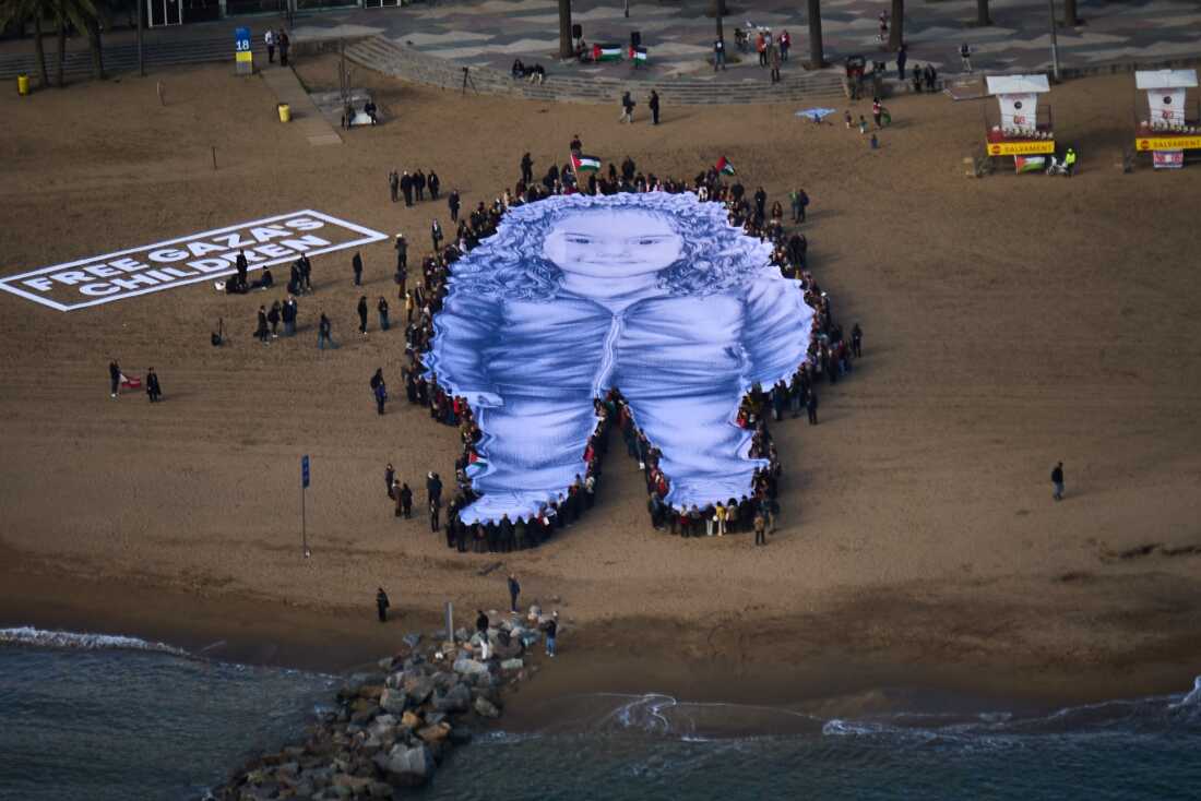 People hold a giant portrait of Hind Rajab, a five-year-old Palestinian girl who was killed during the war in Gaza, on a beach in Barcelona, Spain, Thursday, Jan. 29, 2026.