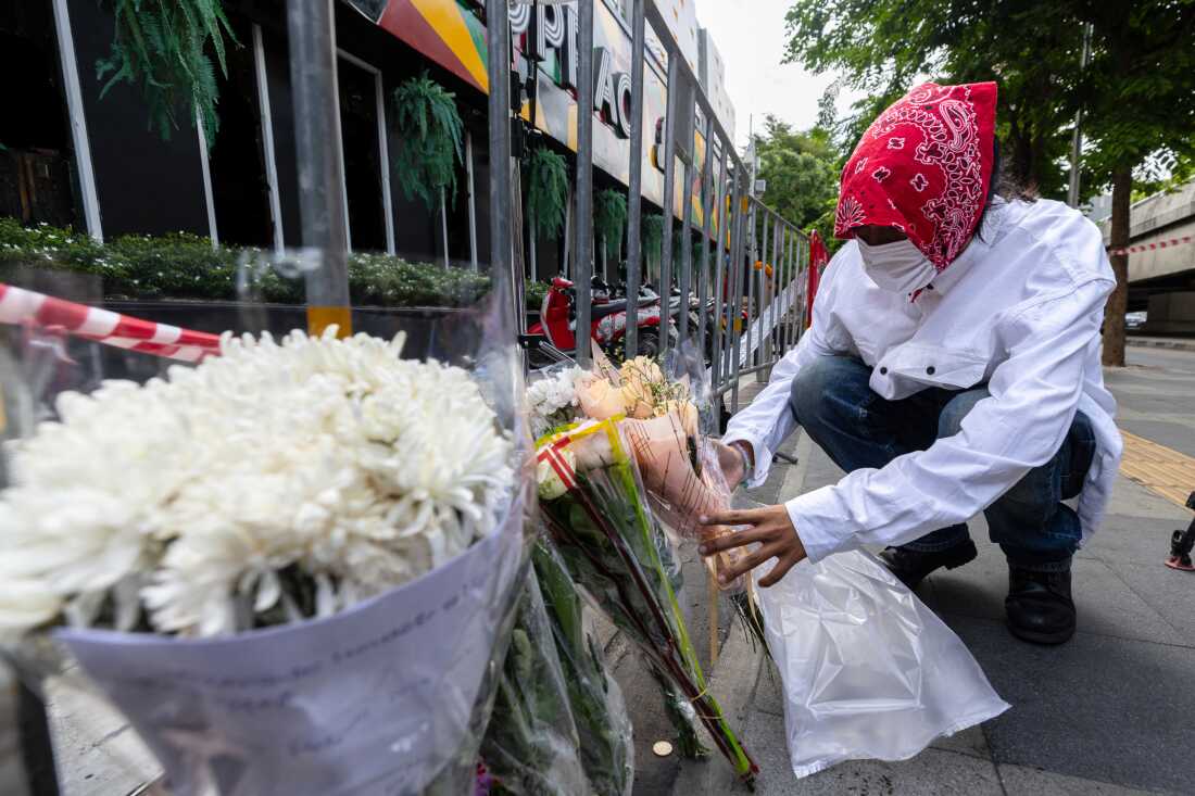 Bir adam, 14 Temmuz 2026 Salı günü Bangkok, Tayland'da çıkan yangında çok sayıda kişinin öldüğü müzik barının önüne çiçek koyuyor.