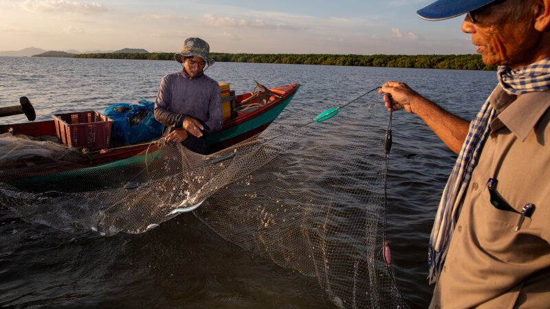Local fisheries on the coast of Cambodia struggled with decimated fish populations for years. Today, they are teaming with seafood, thanks to local ecological restoration efforts. Here, on right, Koh Kresna village chief Khiev Sat talks with a fisherman about the day&rsquo;s catch.