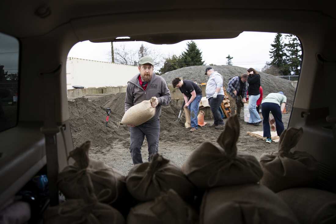 Jason Prescott puts filled sand bags into his vehicle in Mount Vernon, Wash., on Thursday.