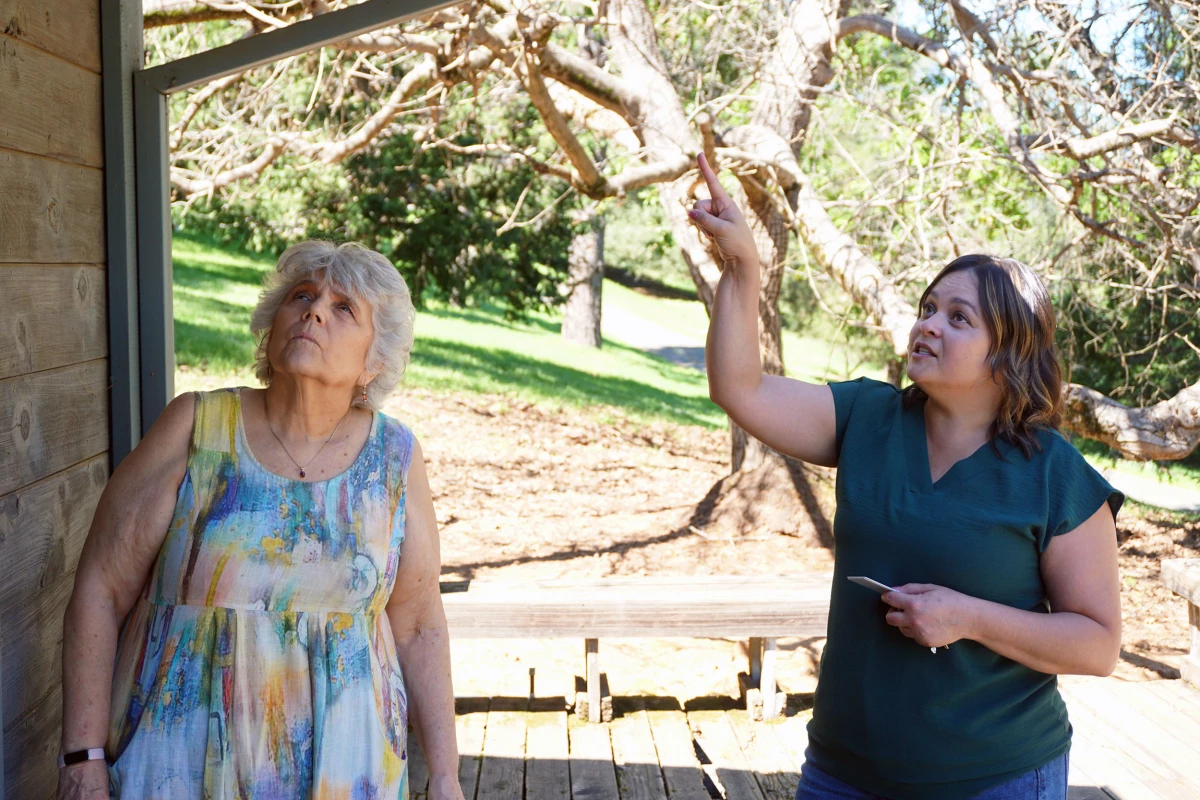 El Dorado County wildfire resilience officer Tanya Harlow looks at the home of Placerville resident Adele Montgomery. Her house is part of a new program to retrofit houses with fire-resistant materials, but has been stalled for a year due to delays at FEMA.