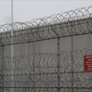 Barbed wire fencing is shown behind a sign in English and Spanish in a recreation yard used by detainees during a media tour of the U.S. Immigration and Customs Enforcement detention center in 2019 in TacomaWash.