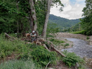 Kyle Cresap clears debris tangled in fallen logs outside of Burnsville, N.C. in May 2026.