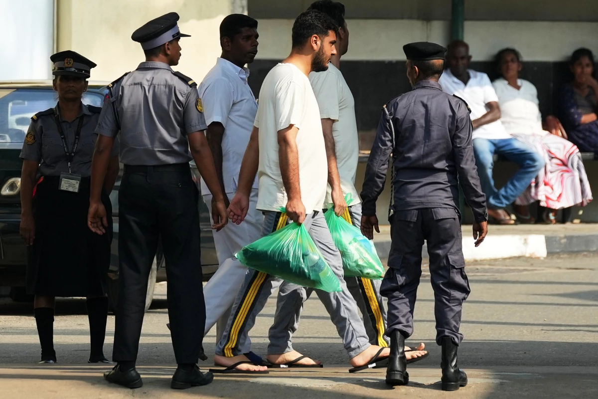 Two Iranian sailors, center, who were rescued from IRIS Dena warship by Sri Lanka's navy are escorted to a Judicial Medical Officer from the National Hospital, in Galle, Sri Lanka, Thursday, March 5, 2026. (AP Photo/Eranga Jayawardena)