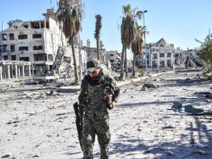 A member of the Syrian Democratic Forces (SDF) walks through a heavily damaged a street leading to an Armenian church in Raqqa on October 18, 2017. The SDF fighters flushed jihadist holdouts from Raqqa's main hospital and municipal stadium, wrapping up a more than four-month offensive against what used to be the inner sanctum of ISIS's self-proclaimed