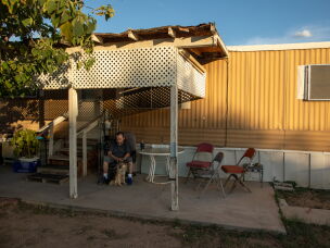 Paul Valdez and his dog, Gunner, sit in the shade outside his home in Tucson, Arizona. The electricity in Valdez's mobile home park has gone off for hours at at time during the hottest parts of the year. Valdez is diabetic, and he worries about heat exposure.