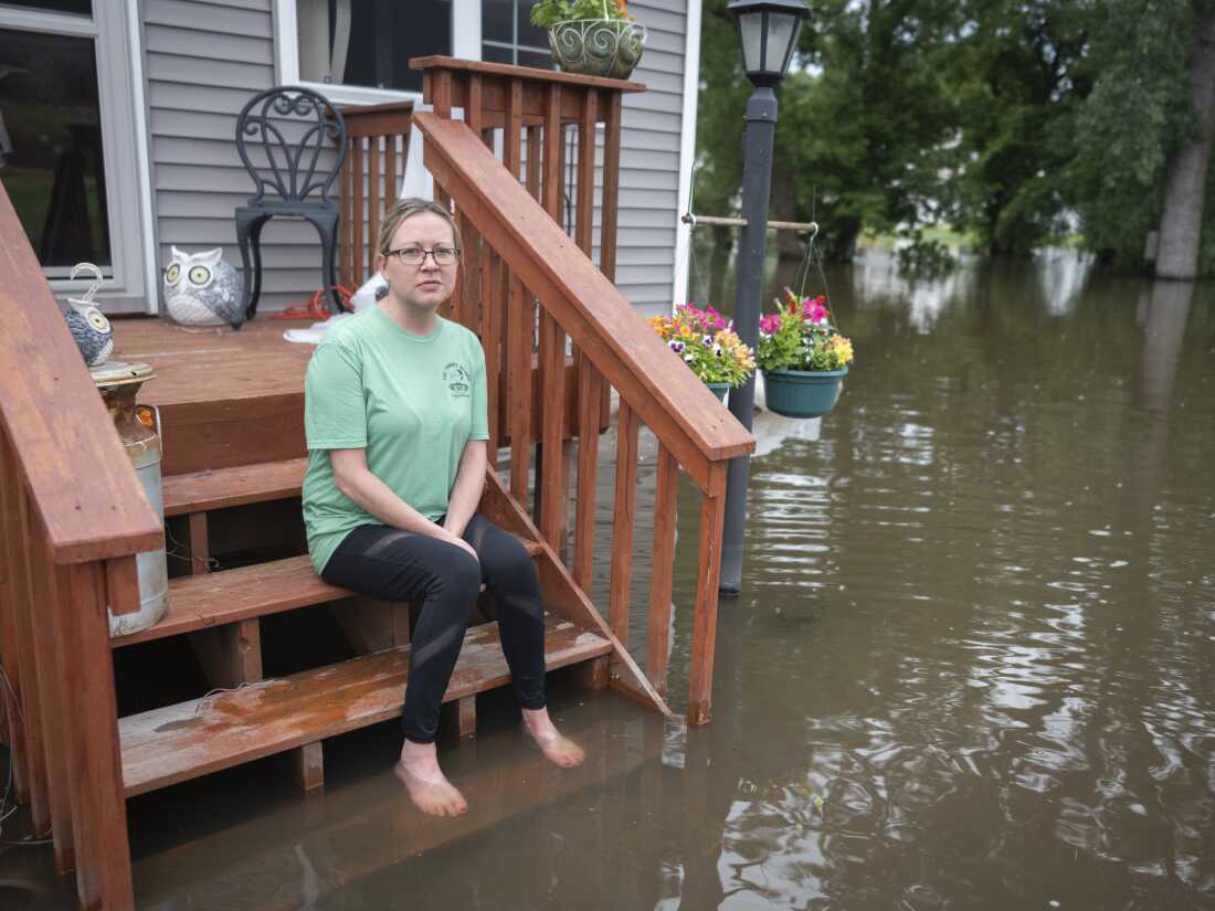 Rachel Morsching sits Tuesday on the flooded porch of her father Dean Roemhildt's home in Waterville., Minn. Waters from the nearby Tetonka and Sakatah lakes have encroached on the town amid recent heavy rains.