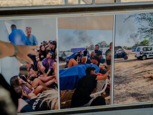Meir Zohar points to documentary photographs at the Nova festival memorial site. The center photograph shows his wounded daughter, Bar Zohar, receiving emergency treatment in the final minutes of her life on Oct. 7, 2023.