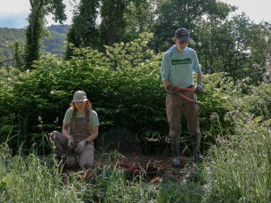 Haley Smith, left, and Michael Crooks, right, remove garbage and debris from the banks of a creek north of Asheville, N.C. Both are experienced outdoor recreation professionals who have turned to debris cleanup since Hurricane Helene hit the area in 2024.