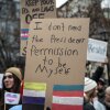 A homemade sign with black marker on brown cardboard reads, "I don't need the President's permission to be myself."