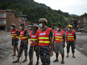 Rescue team personnel search through debris and mud covering an area following flash floods in DeviGhat village, Nepal.