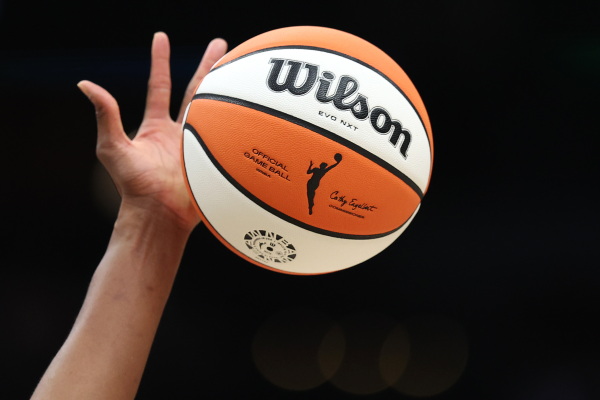 The WNBA logo on the ball is seen as it is tipped during the game between the Seattle Storm and the Las Vegas Aces last year in Seattle, Wash. The WNBA has announced it's expanding to a record 18 teams — adding three new franchises: Cleveland, Detroit and Philadelphia.
