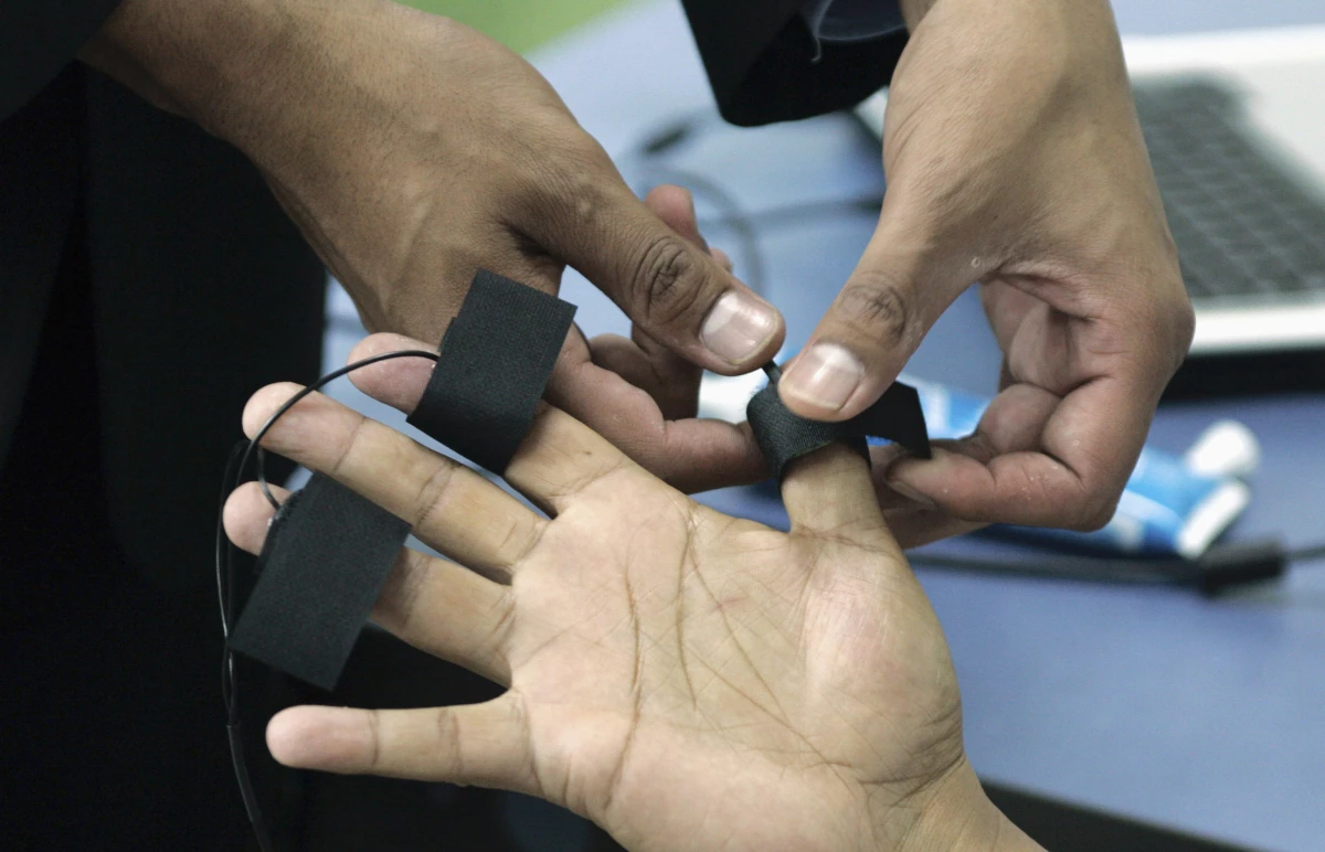 A polygraph examiner applies electrodes on the fingers of a subject in Bogota, Colombia on June 12, 2007.