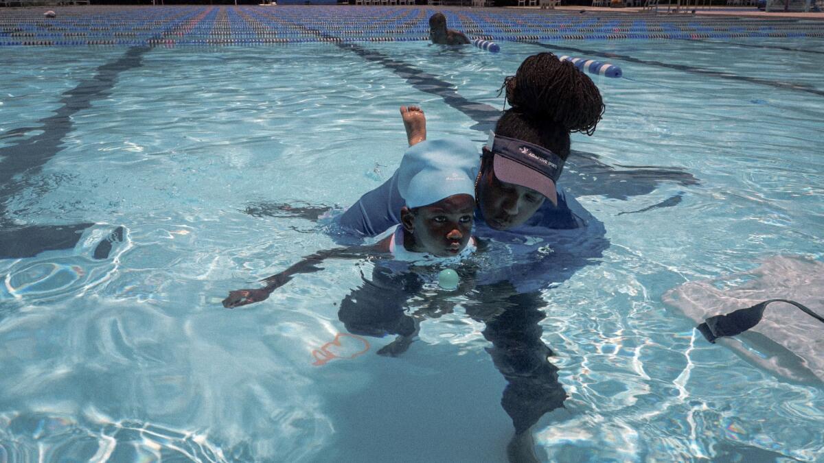 Garland Jones, recreational therapist and senior program director of the YMCA of South Florida's special needs program, teaches Mackenzie Wesley, 5, to breathe safely in water by using a ping pong ball as a visual aid.