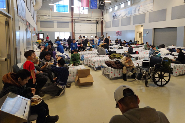 Evacuees from Kipnuk and Kwigillingok rest and eat dinner on Oct. 15, 2025 at an emergency shelter at the Alaska National Guard Readiness Center in Bethel.