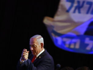 Israeli Prime Minister Benjamin Netanyahu gestures to his supporters at the election night rally after the first exit polls were announced Tuesday, in Jerusalem.