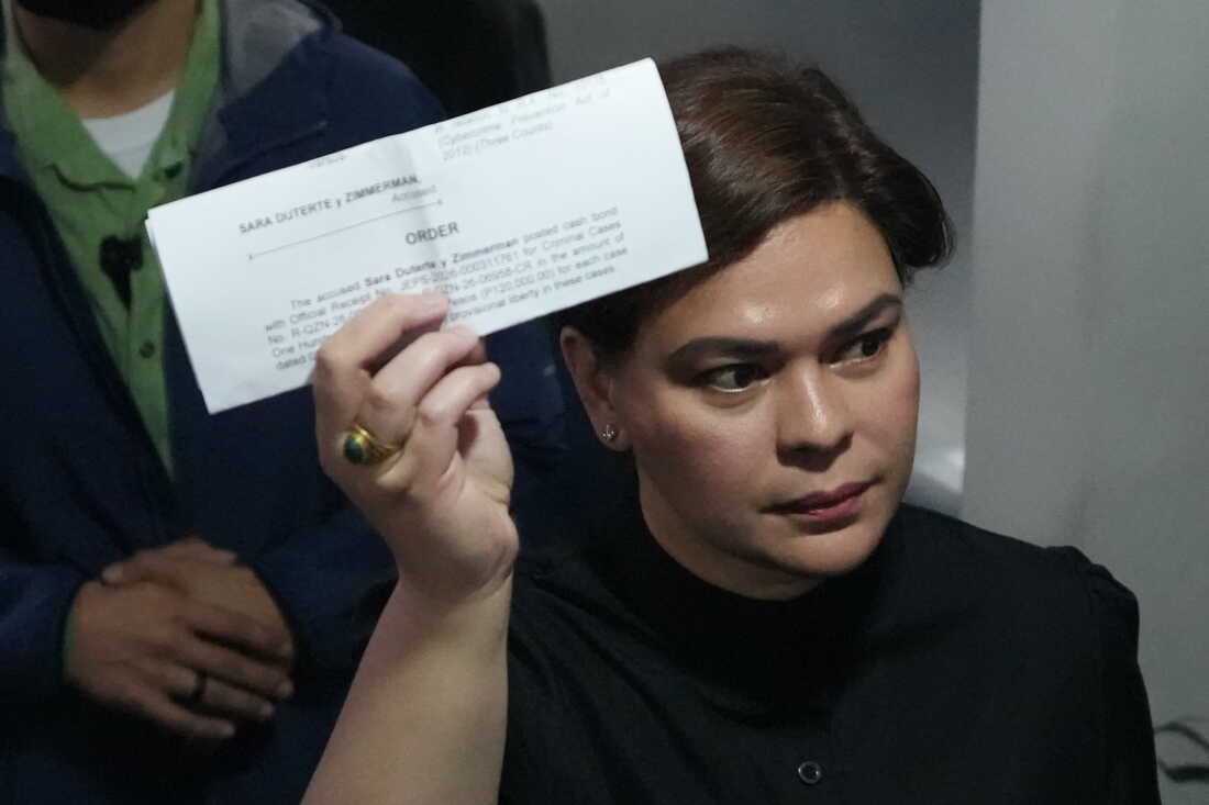 Philippine Vice President Sara Duterte shows a document to reporters at the Quezon city justice hall Saturday, Sept. 5, 2026, after an arrest warrant was issued on charges that she publicly threatened to have the president and two other people assassinated.