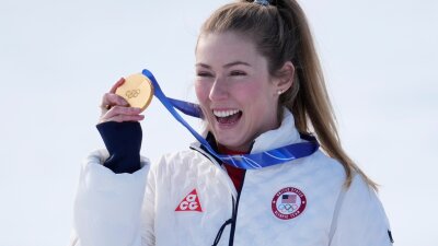 Mikaela Shiffrin from Colorado holds up her gold medal hanging around her neck.