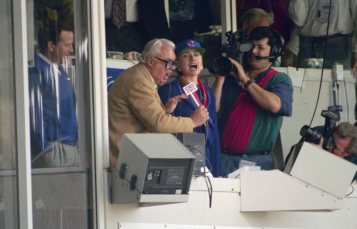 Hillary Clinton, middle, who was First Lady at the time, and Chicago Cubs announcer Harry Caray, left, sing 'Take Me Out To The Ball Game' during the seventh inning stretch at Wrigley Field in Chicago in 1994.