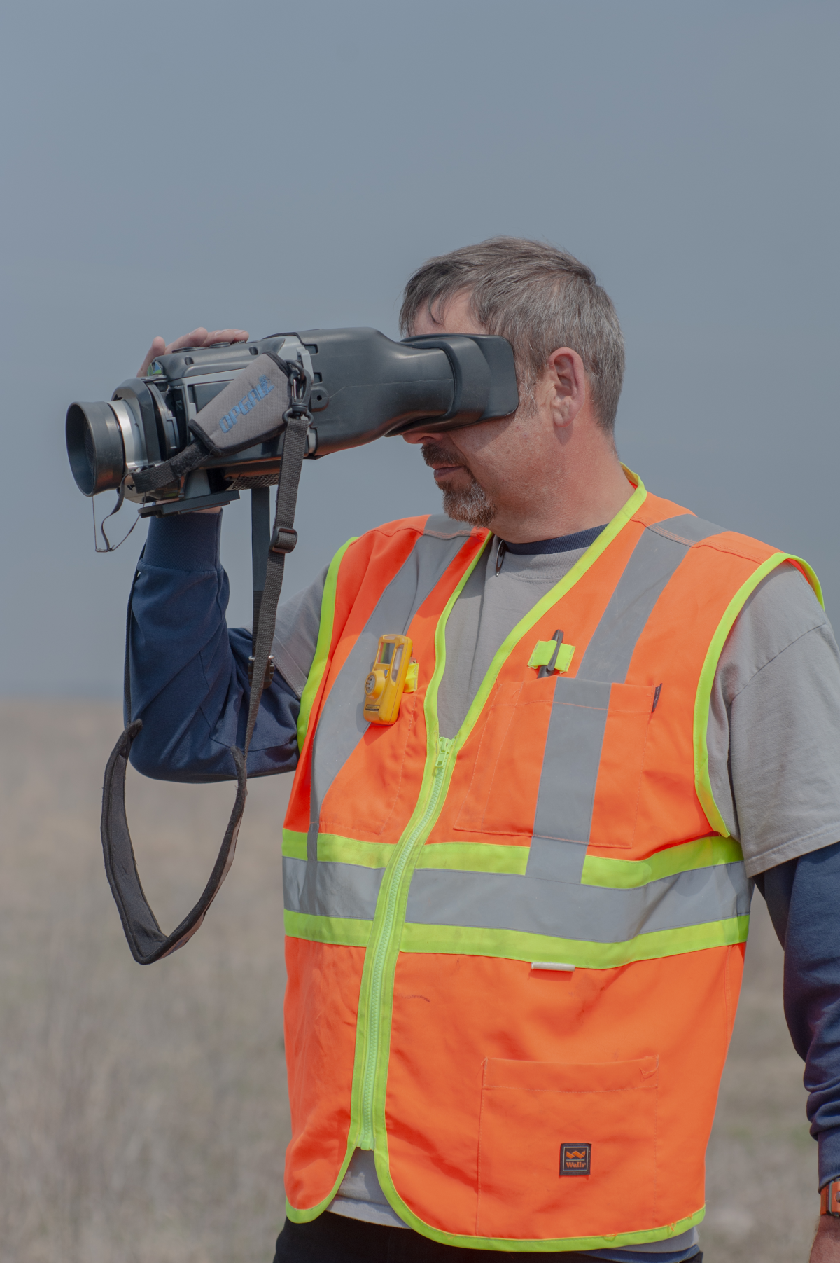 Daniel Caldwell, a technician for Arthur's company, ALL Consulting, looks through an optical gas imaging camera at an oil well in the Tallgrass Prairie Preserve in Oklahoma on March 20, 2024.