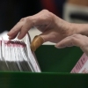 This photo shows the hands of an election worker who is processing ballots at the Clark County Election Department in Las Vegas on Nov. 10, 2022. The hands are flipping through numerous ballots that are filed in a box.