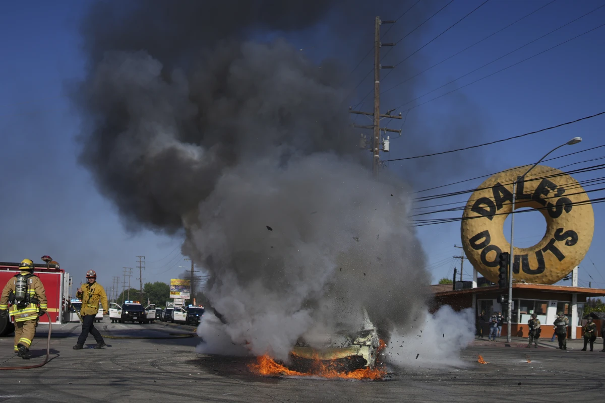 Firefighters respond to a car burning during a protest in Compton, Calif., Saturday, June 7, after federal immigration authorities conducted operations.