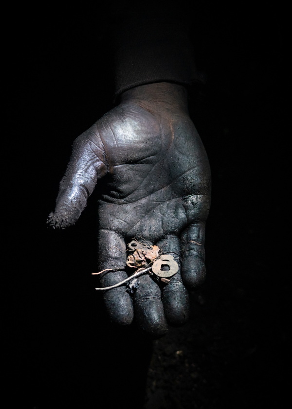 Old Fadama in Accra, Ghana, June 12, 2023. Working through the night, Awimbela sifts through the soil to retrieve small pieces of copper and iron left over from the burning of waste electrical cables.