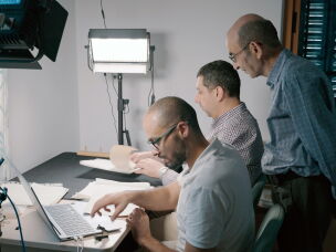 Yazeed Abu Khdeir (left) and Mahmoud Muna work to digitize papers, as Raja Shehadeh (standing) looks on.<br>