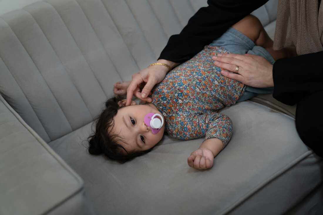 Soha Sakallah tries to coax her granddaughter, Mariam, to sleep on the sofa.