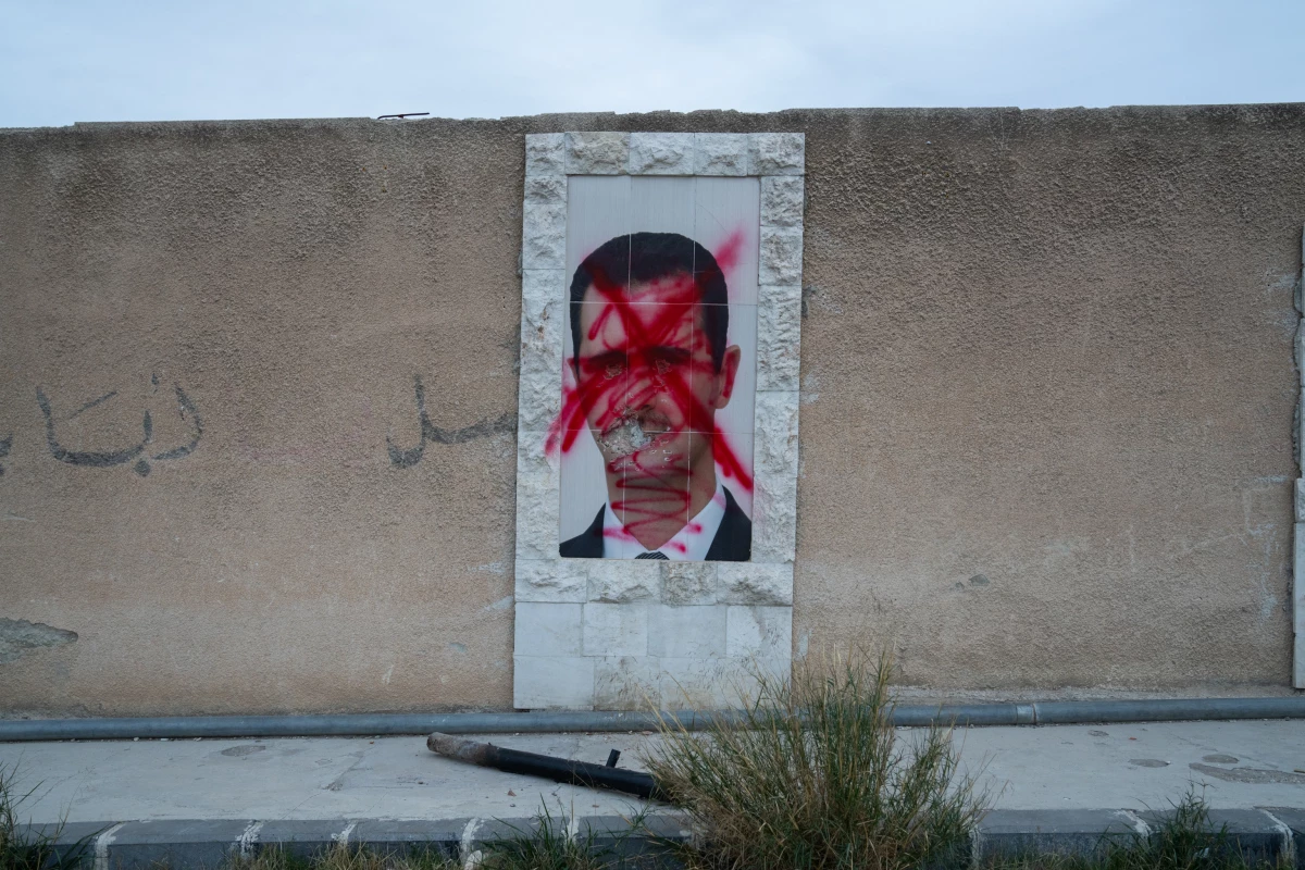 A poster of Bashar al-Assad is defaced with red paint on a wall in Damascus, Syria, on Dec. 11.