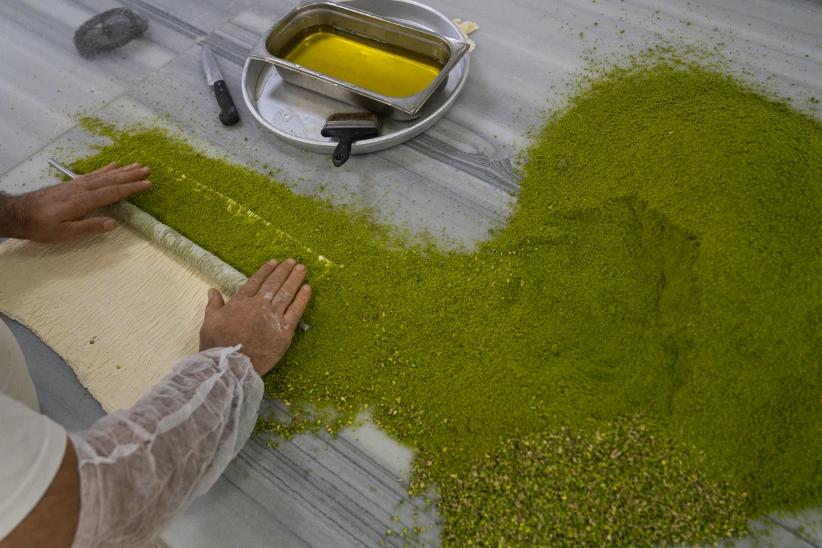 A baker rolls chopped pistachios into baklava dough at the Celebiogullari factory.