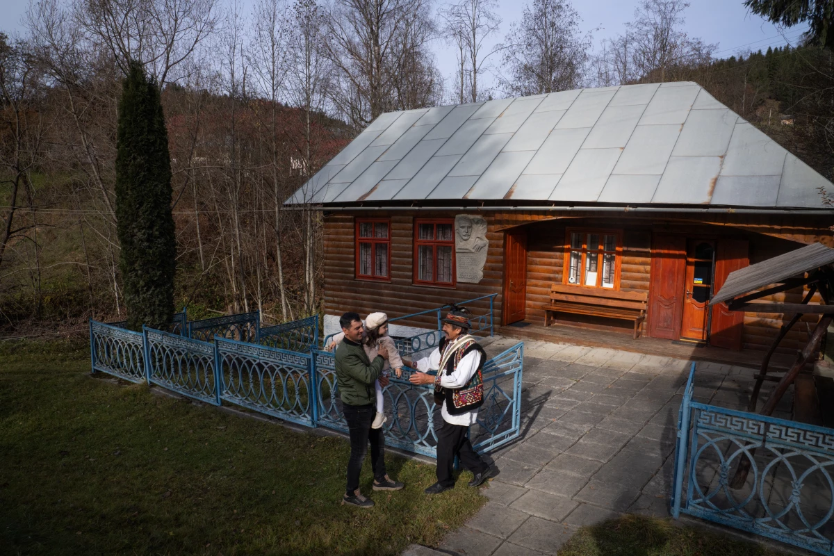 Volodymyr Sinitovych, director of the Hutsul Theater, greets his son and grandchild outside the small museum in Krasnoillya, where the history of Hutsul theater is documented and sometimes performed.