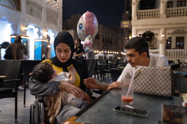 Raneem Hijazi (left) holds her baby, Mariam, while sitting next to her husband, Asaad Sakallah, at an outdoor cafe in Doha, Qatar. Until this summer, Hijazi was in Qatar by herself getting treatment. Now having the whole family around has livened up her life.