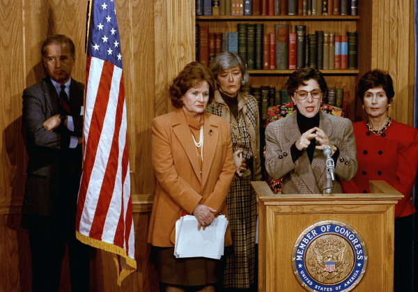 Sen. Joe Biden, D-Del., stands behind a flag as Sen. Barbara Boxer, D-Calif., discusses the Violence Against Women Act on Capitol Hill on Feb. 24, 1993.