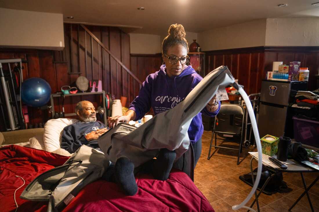 Dawnita Brown helps her father, Bill, use a compression machine on his legs. Her father lives in the basement of the home.