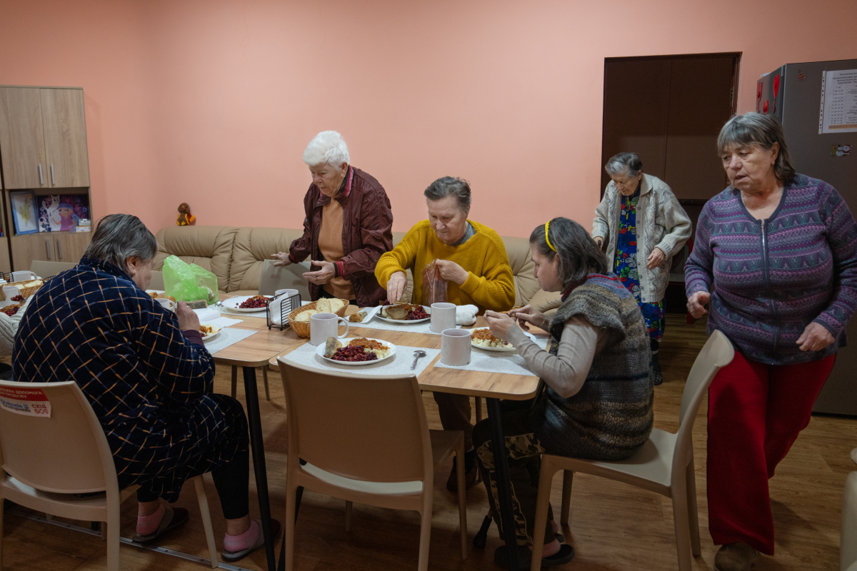 Internally displaced people staying at the ARTAK shelter in Zaporizhzhia gather for dinner. Anastasia found a sense of community by volunteering at ARTAK, where she helps other displaced people, including seniors and the disabled. It's like family, she says.