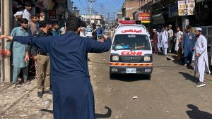 A volunteer clears the way for an ambulance transporting injured school children following a roof collapse at a private school in Peshawar, Pakistan, Thursday, Oct. 15, 2026.