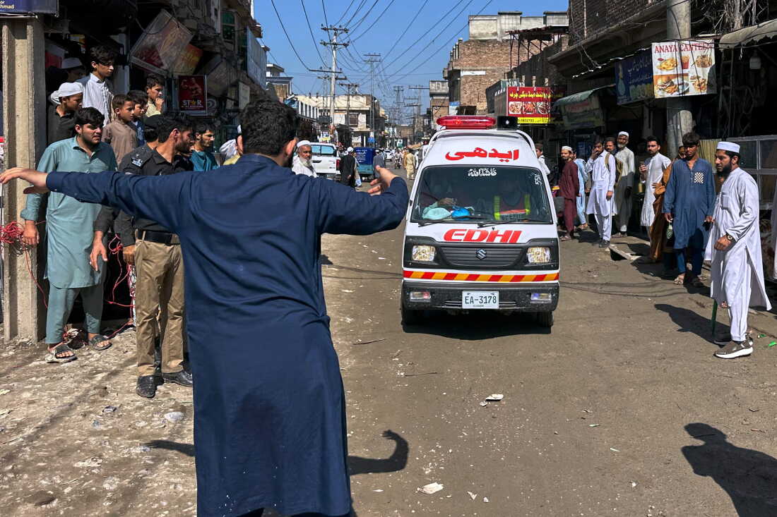 A volunteer clears the way for an ambulance transporting injured school children following a roof collapse at a private school in Peshawar, Pakistan, Thursday, Oct. 15, 2026.