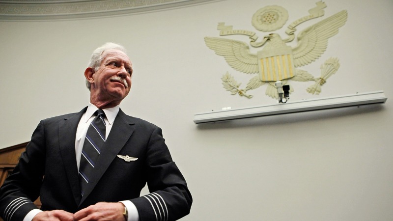 US Airways Captain Chesley "Sully" Sullenberger stands, buttoning his suit jacket, as he prepares to testify before a House Judiciary subcommittee on Capitol Hill on December 16, 2009.